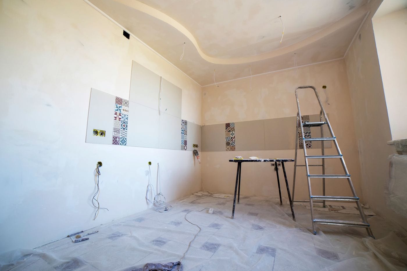 Ceramic tiles being set over a board-lined wall